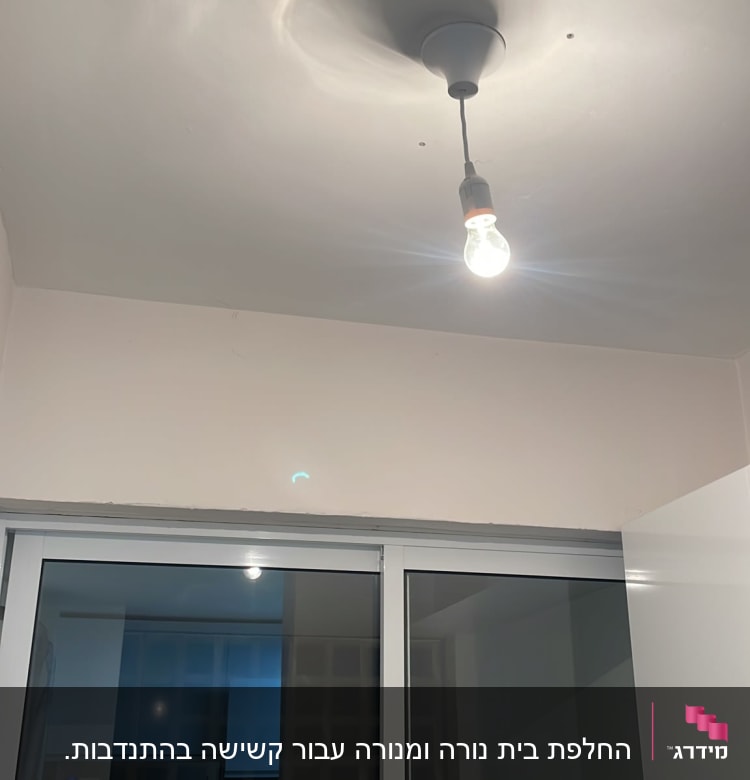 נורה חשמלית תלויה מהתקרה בחדר מואר